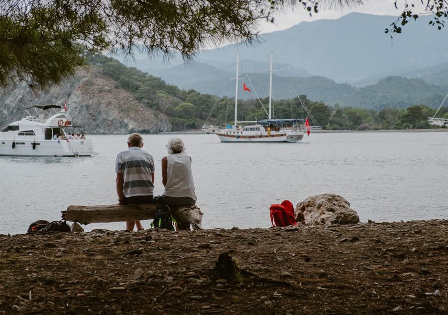Older couple on a bench looking over a bay with sailboats