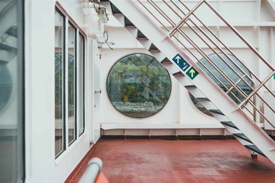 Outer deck of a ship with steel stairs and a round window