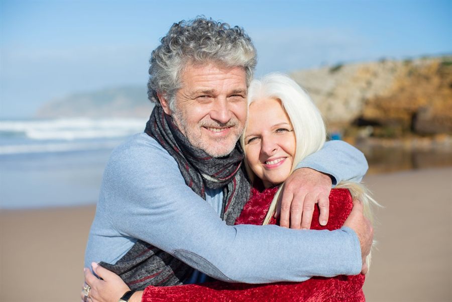Older couple hugging on a sunny beach