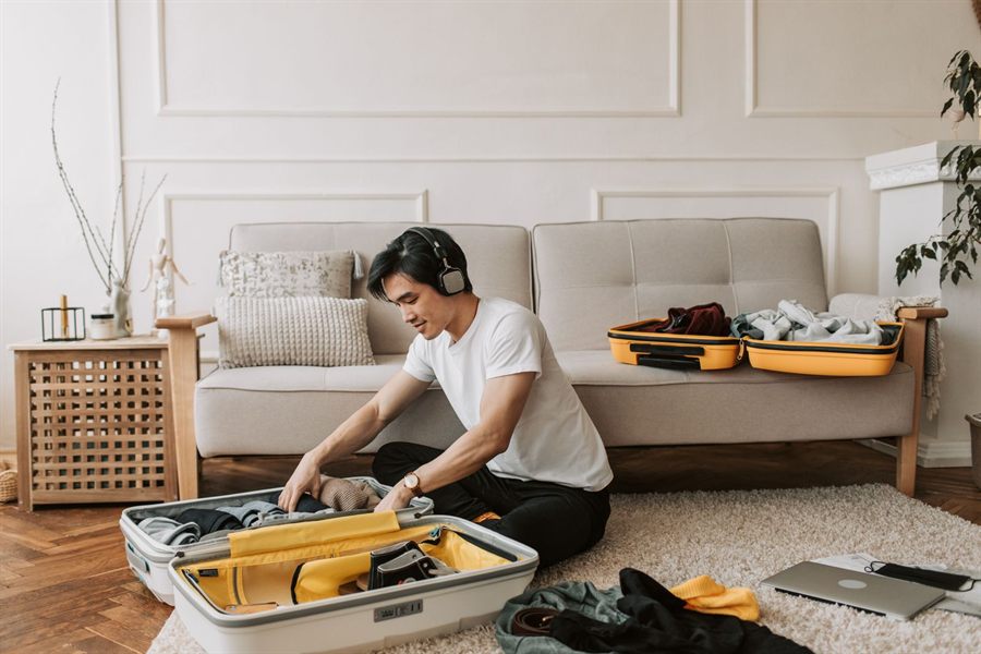 Young man packing a suitcase on a living room floor