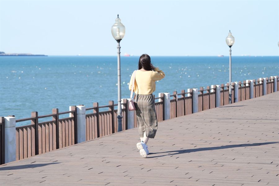 Woman walking alone along a seaside promenade