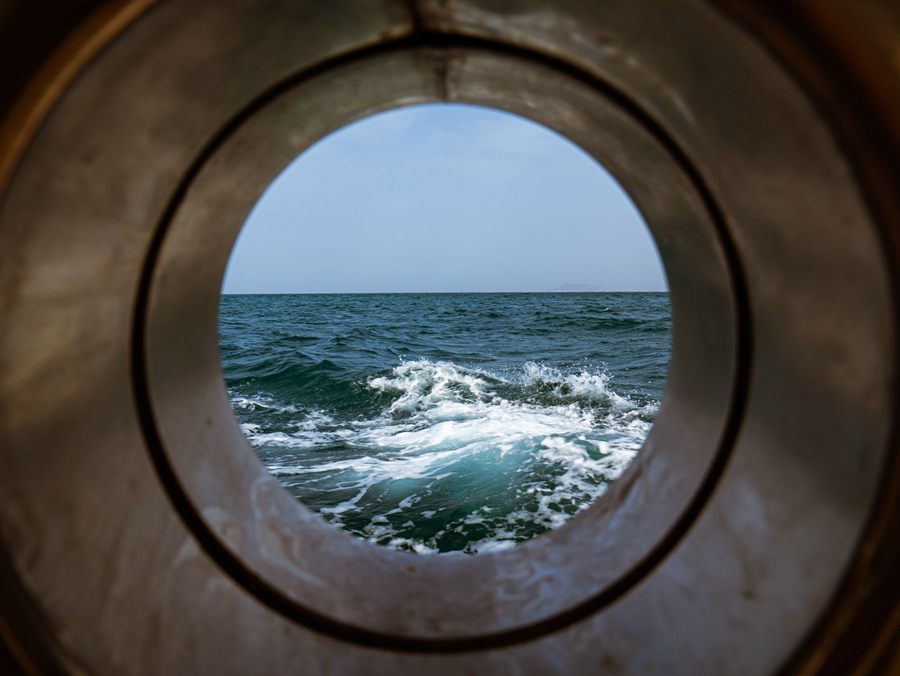 Waves breaking seen through a brass-rimmed porthole