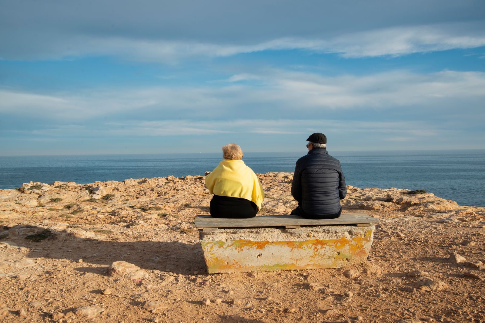 Retired couple on a seaside bench, the flexible travelers unsold cruise cabins for seniors suit