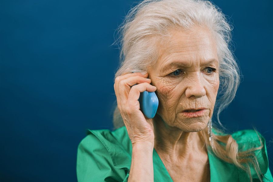 Gray-haired woman listening carefully on a mobile phone