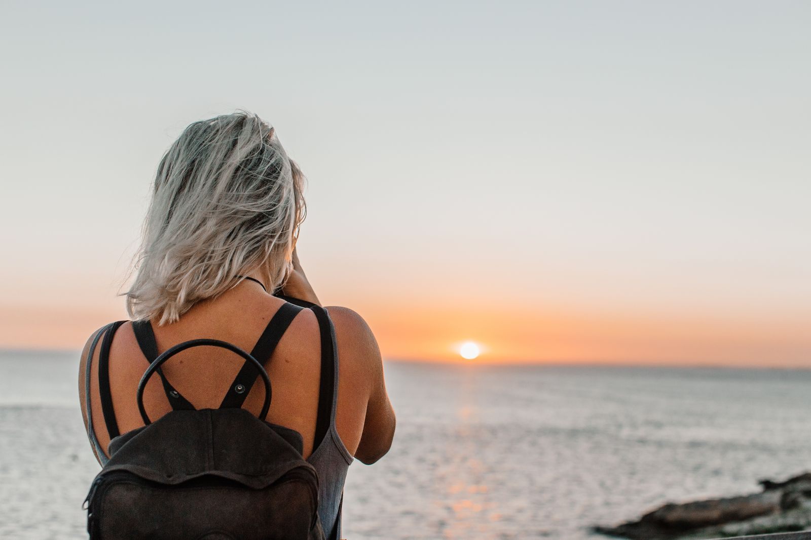 Woman traveling alone watching the sun set over the sea, a typical guest on unsold cruises for one person